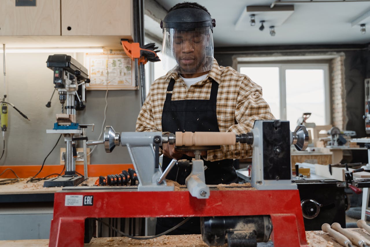 services-02 A professional craftsman using a wood lathe in a workshop, focusing on precise woodworking skills.